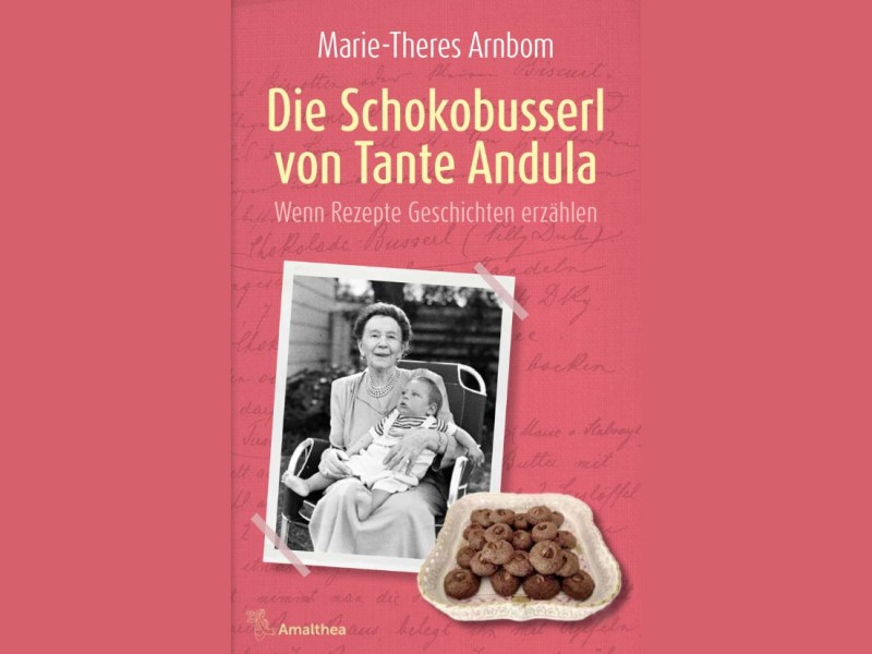 Buchcover mit Foto einer Frau und einem Kind auf dem Schoß sowie einem Teller mit Schokobusserln vor rotem Hintergrund mit dem Titel 'Die Schokobusserl von Tante Andula' von Marie-Theres Arnbom