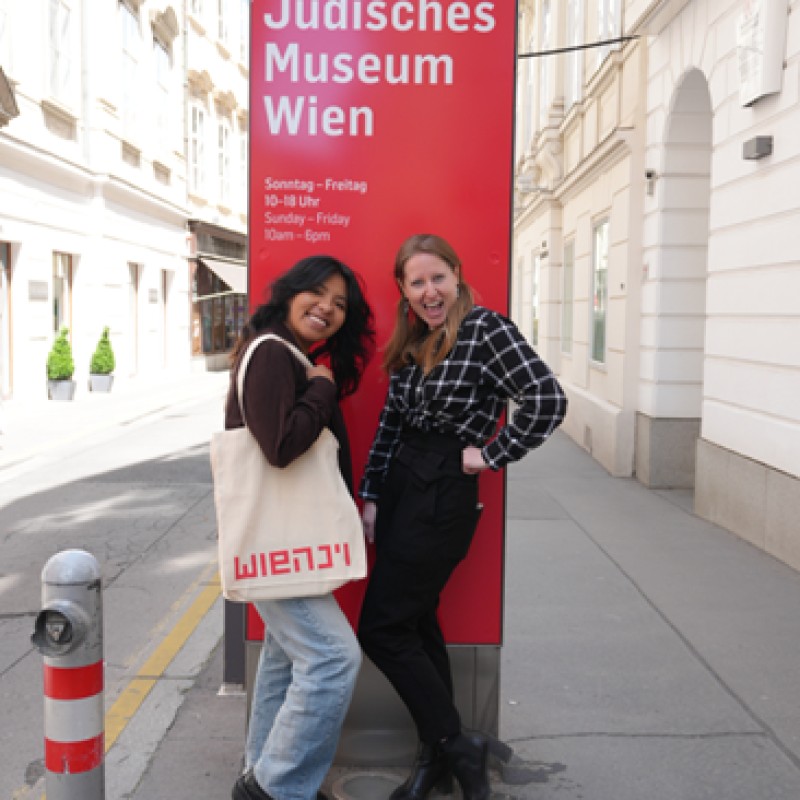 : Zwei junge Frauen lächeln vor dem Jüdischen Museum Wien.