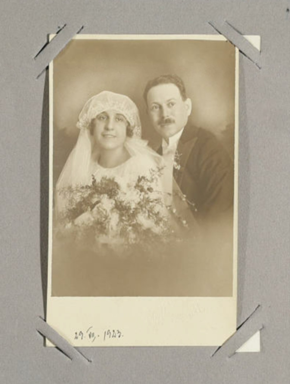 : Schwarzweiß-Hochzeitsfoto von einem Brautpaar, die Braut trägt Schleier und hält Blumen, das Datum 29.VII.1923 ist unten handschriftlich notiert
