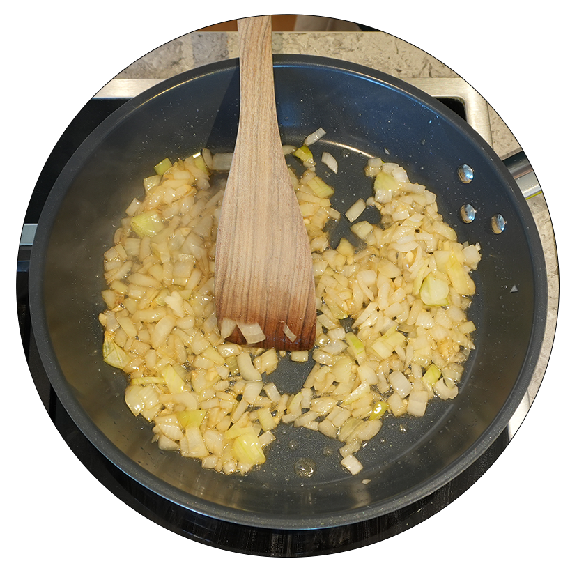 Eine Pfanne mit angebratenen Zwiebeln, die goldbraun sind. Ein Holzlöffel rührt die Zwiebeln um. Dampf steigt auf.