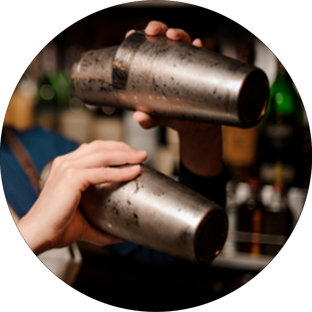 Hände halten zwei Metall-Shaker übereinander in einer Barumgebung