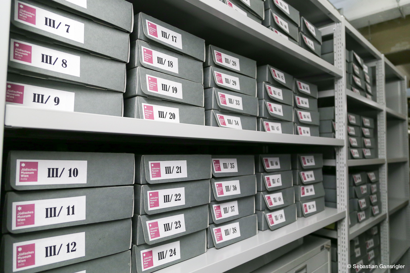 Regal mit grauen Archivboxen des Jüdischen Museums Wien, beschriftet mit Nummern von III/7 bis III/49